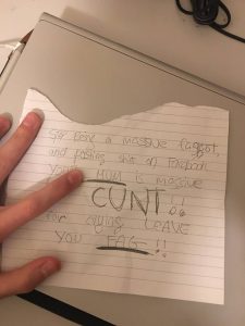 A note reading "Stop being a massive faggot, and posting shit on Facebook, your mum is a massive cunt!! for crying, leave you fag!!"