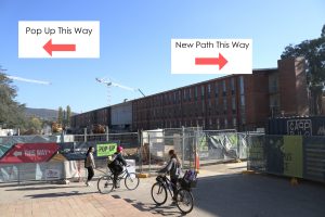 Photo of the construction with signs showing the pop-up one way, and the new path the other way