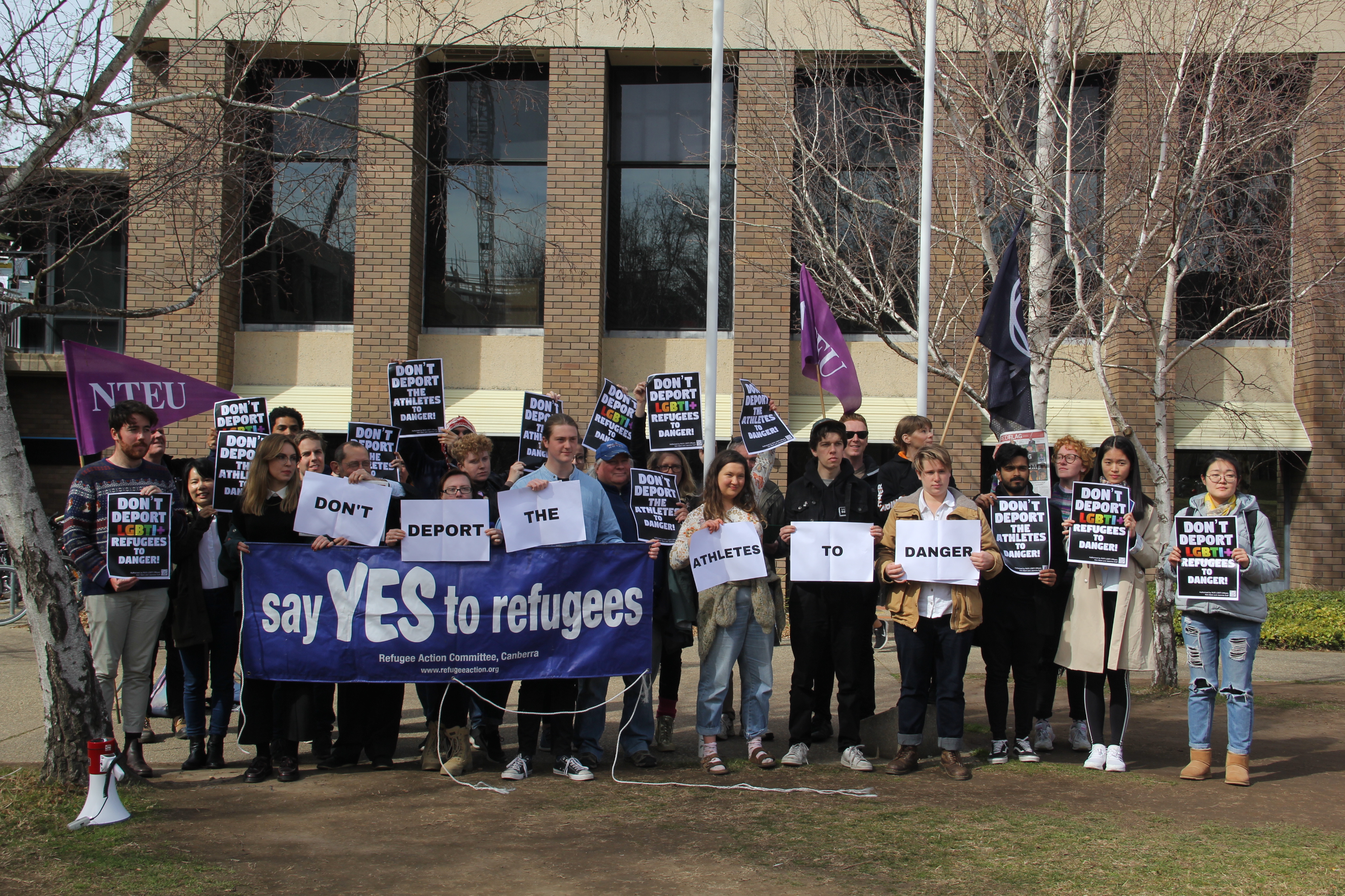 Approximately 20 students with banner 'say YES to refugees'