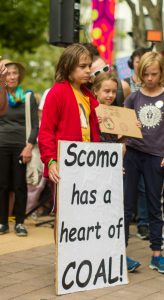 A child holds a sign saying "Scomo has a heart of coal"
